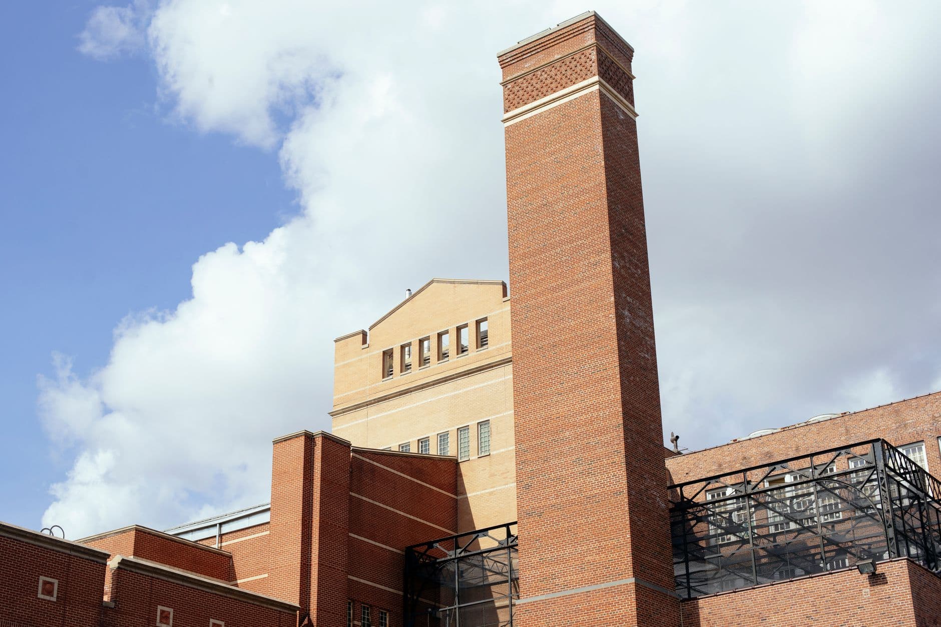 From below of exterior of contemporary building facade made of red brick under cloudy sky